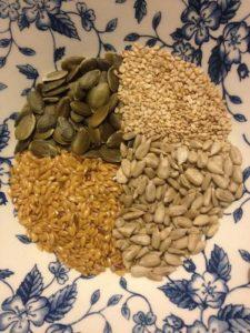 4 types of seeds in a bowl with a blue floral design
