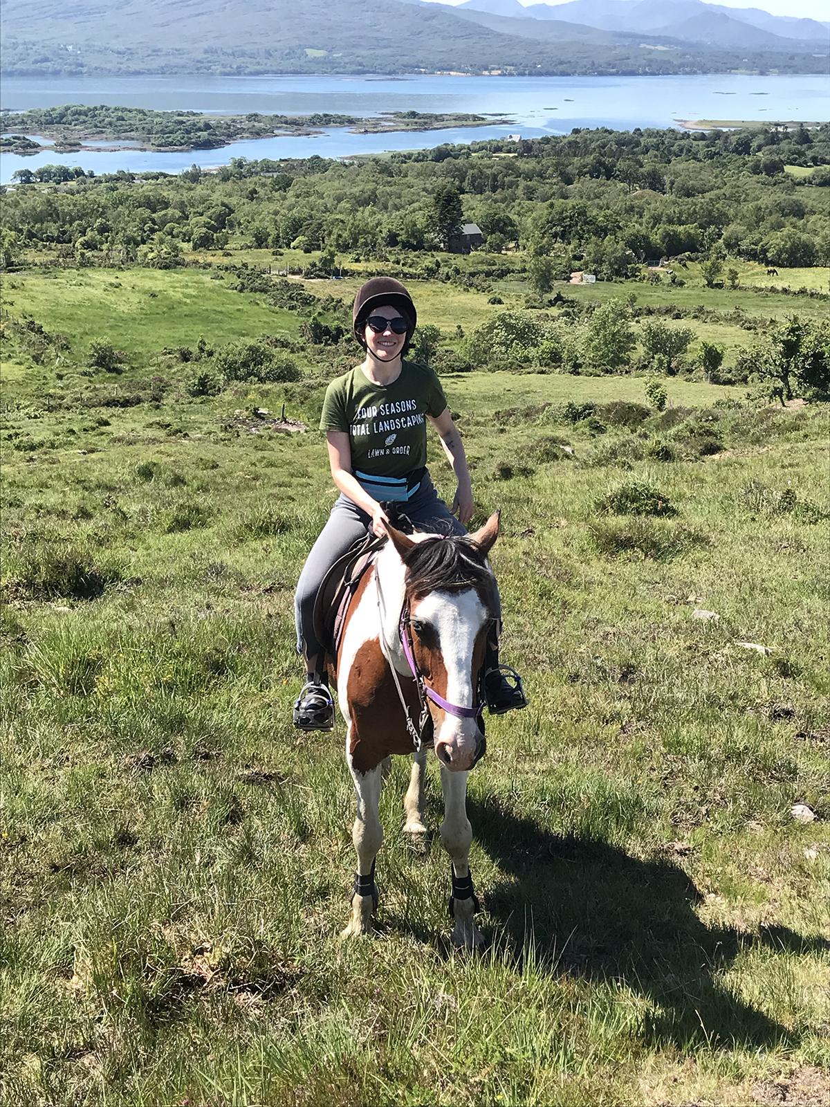 Helen on a horse in the countryside. sea, islands and mountains in background